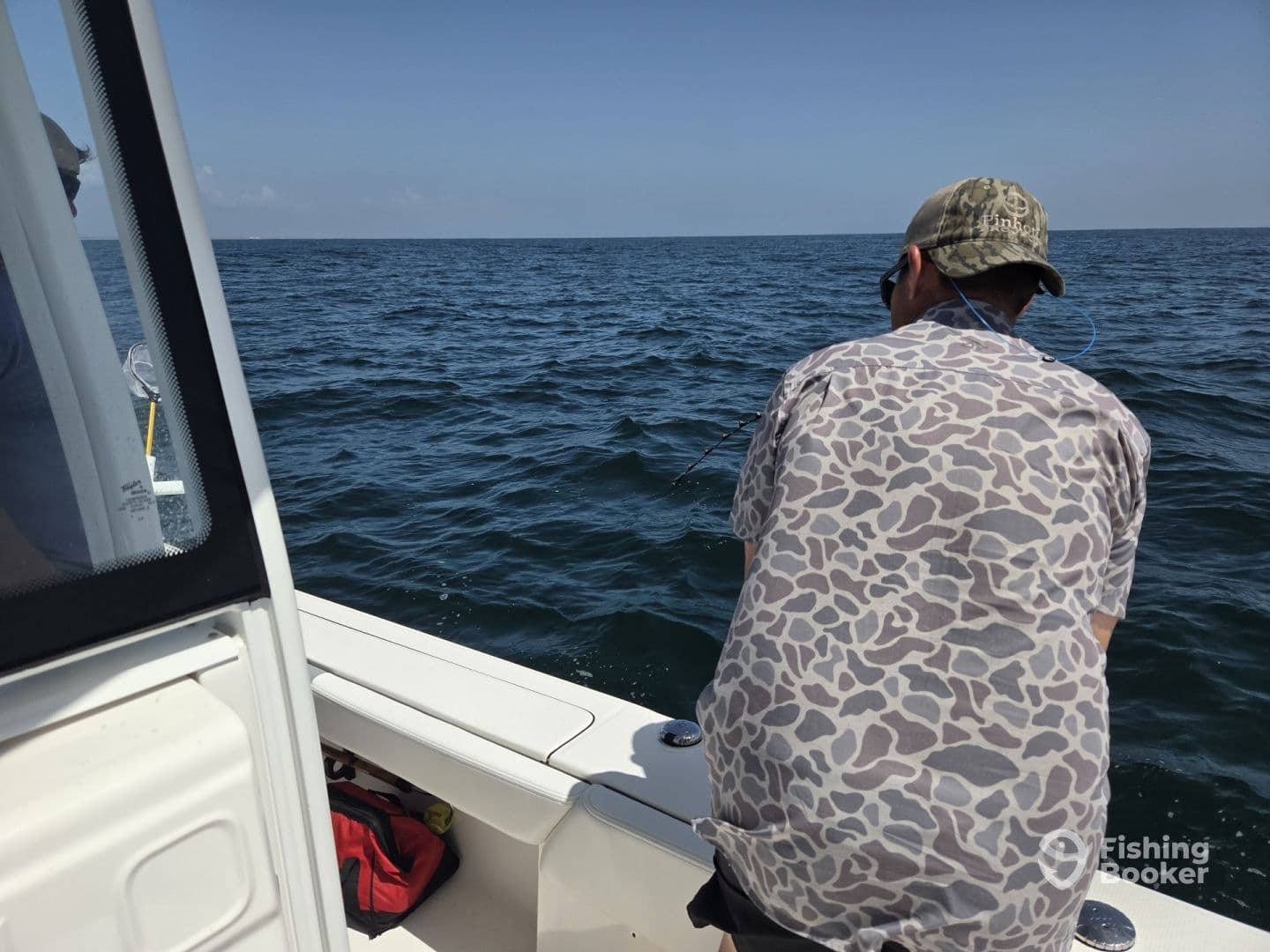 An angler actively reeling in a catch while fishing on a boat in open water, showcasing the excitement of the fishing experience.
