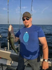 Angler proudly displaying a Walleye caught while fishing on a boat in open waters.