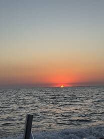 A stunning sunset over the ocean, captured from a boat, showcasing the serene beauty of the fishing environment.