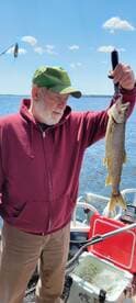 An angler proudly displaying a Northern Pike while fishing on a sunny day, showcasing the excitement of a successful catch.