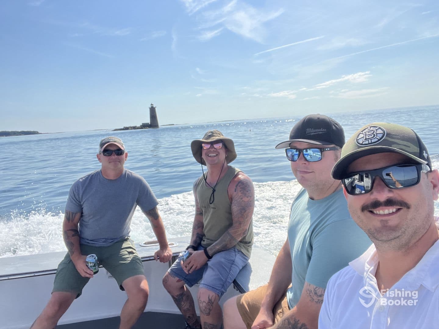 Group of four friends enjoying a sunny day on a fishing boat, with a lighthouse visible in the background.